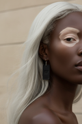 Elegant Black albino woman wearing KW signature leather medium dangle earrings